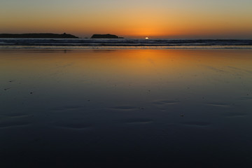 Wet sand at low tide on a sunset background