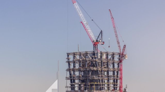 Construction progress of new modern skyscraper in Dubai city aerial timelapse, United Arab Emirates. Cranes and building equipment in financial district near downtown