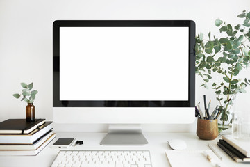 Clean neat workspace of creative freelancer with computer, books, stationary tools and green plants on white table. Electronic gadgets and office supplies for distant work. Occupation and technology