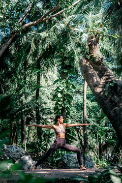 Get the gear that never gives up. Full-length shot of caucasian woman standing in Warrior II pose, Virabhadrasana while practicing yoga outdoors, in a garden. Healthy lifestyle and relaxation concept