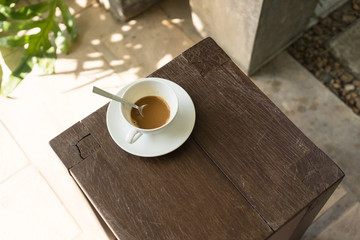 A cup of coffee on wooden chair.