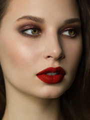 Close-up portrait of the cleanliness face of a beautiful woman with dark black smoky eyes makeup, red full lips. Sexy model with clean shiny skin, clean face, long curly hair. glamorous image