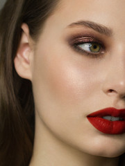 Close-up portrait of the cleanliness face of a beautiful woman with dark black smoky eyes makeup, red full lips. Sexy model with clean shiny skin, clean face, long curly hair. glamorous image