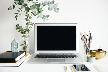 Close up minimalist shot of generic laptop computer and working accessories resting on white table. Workplace of unknown freelancer or student. Electronic gadgets, communication and networking