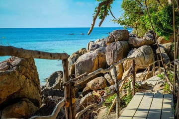 Fototapeta na wymiar The beautiful view at Lipe island, Satun, Thailand. The scenery wooden bridge and rock beach with clear sea water.