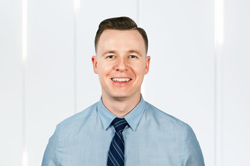 Portrait of young smiling guy, businessman dressed in blue shirt and tie