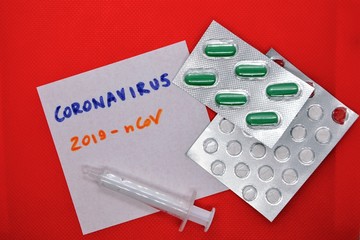 Novel coronavirus (2019-nCoV) lettering on the sheet of paper, medical pills in blister and...
