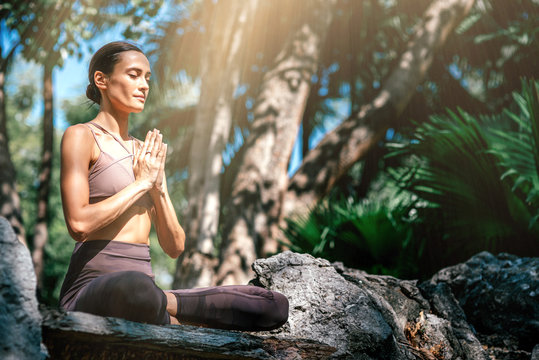 Listen to your soul. Full-length shot of caucasian woman sitting in Easy Seated pose, Sukhasana while practicing yoga outdoors, in a garden. Healthy lifestyle and relaxation concept