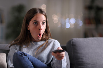 Surprised woman watching tv at home in the night