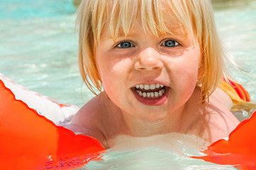 Kleines Kind erlernt im Freibad das Schwimmen