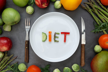 Diet concept. Round plate with word - diet - composed of slices of different fruits and vegetables...