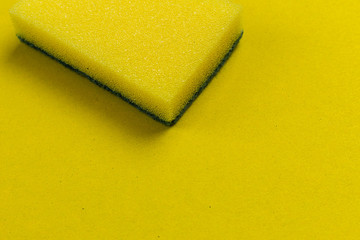 Yellow dishwasher sponge on a yellow background