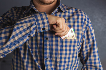 Close up hand of a man in a plaid shirt holding banknote into pocket. Man pulls money out of his breast pocket. 100 Russian Ruble currency