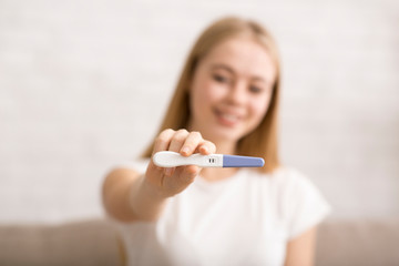 Positive pregnancy test held by young girl