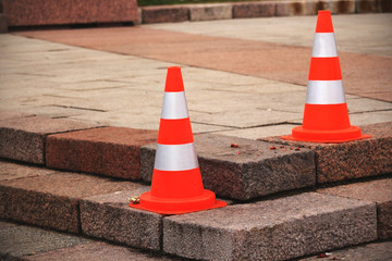 Two road cones standing on a corner of square steps
