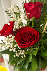 Closeup on floral arrangements. The floral arrangement is three red roses and green leaves. A wonderful gift for a woman.
