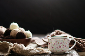 Cup of tea, coffee on an old wooden table against the background of knitting tools.