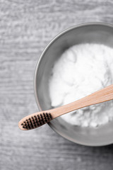 Bamboo toothbrush on a bowl with tooth powder. Top view, eco-friendly lifestyle