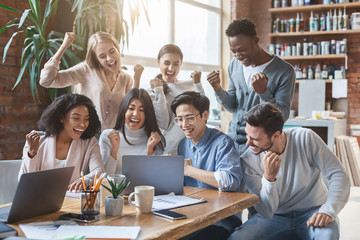 International business team looking at laptop screen, celebrating success