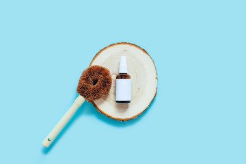 Zero waste kitchen concept. Natural dishwashing detergent in the spray glass bottle and brush for washing dishes on blue background. Flat lay, top view, copy space.