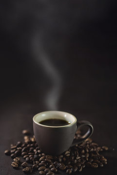  cup of coffee and coffee grains with smoke on a dark background. © Михаил 