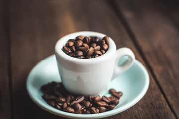 cup with coffee grains on a wooden background.