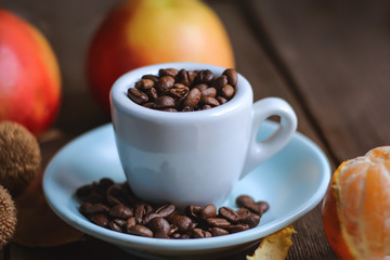 cup with coffee grains and fruits on a wooden background..