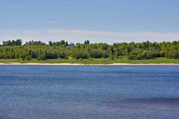 Summer landscape of a river bank, with green forest and village buildings