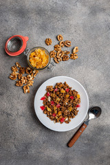 Granola with dried fruits in a white plate on a gray background. Top view. Copy space for text.