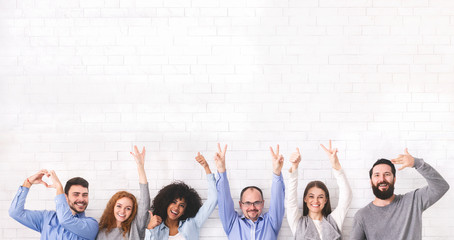 Group of positive people showing funny gestures over white wall background