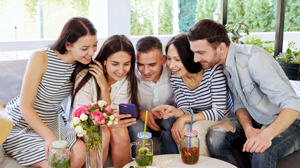 Group of friends are chatting together and drink coctails at cafe.
