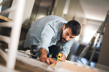 Man measuring side of a baby crib.