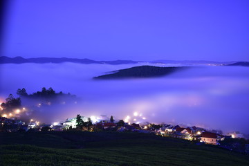 Fototapeta premium long exposure with small village appear in fog and with magical light and sky at sunrise 