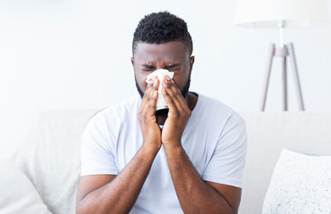 Sick african guy cleaning his snotty nose at home