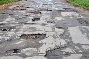 Old destroyed asphalt road with potholes and bumps
