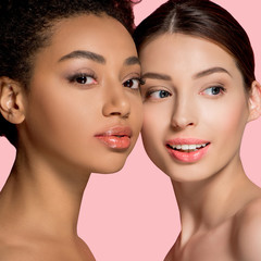 portrait of positive multicultural girls with perfect skin, isolated on pink