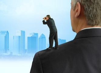 Man with binoculars looking forward standing on the shoulders of giants concept with cityscape representing benefitting from previous work by past people, stock market forecasting, progress & success. - 319200501