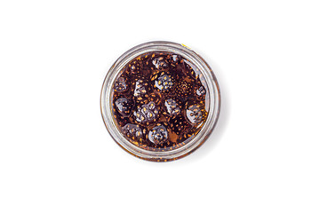 Unusual jam from pine cones in glass jar on white background among pine branches and cones. Organic and vegetarian sweet dessert close up, copy space for text. Remedy for colds