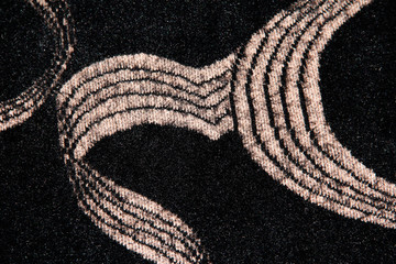 Beige loops on a black background. Textile background with abstraction. Beige striped waves on a fluffy background.