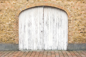 old wooden gate in a brick wall painted with white paint