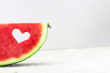 Fresh juicy watermelon slice with heart shape hole on white background. Valentines, love, summer concept