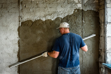 Obraz na płótnie Canvas Construction worker plastering wall with leveler.