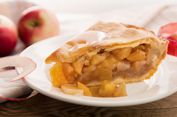 Apple pie piece on white plate on wooden background, close-up