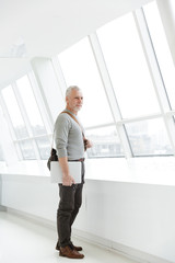 Photo of pleased gray-haired man holding laptop while standing