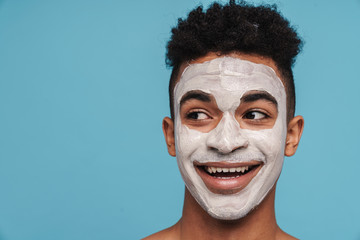 Photo of excited african american man in facial mask smiling at camera