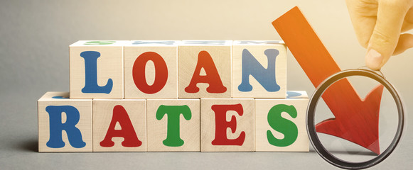 Wooden blocks with the word Loan rates and arrow down. The concept of low mortgage rates. Real estate market. Housing. Credit. Business and Finance