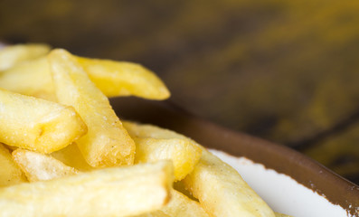 fried French fries on a white plate with brown border on the wooden table