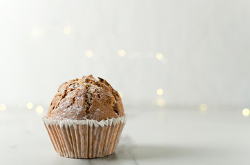 Tasty cupcake without cream on the white table against lights bokeh
