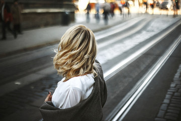 Woman with beautiful fluttering hair stands among a street in the old town