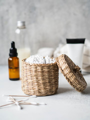 Eco cotton buds in a basket and female body care products. Zero waste concept. Eco-friendly bath set. on a gray background